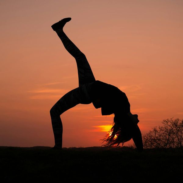 Silhouette of a woman in a dynamic yoga pose with flowing energy lines.