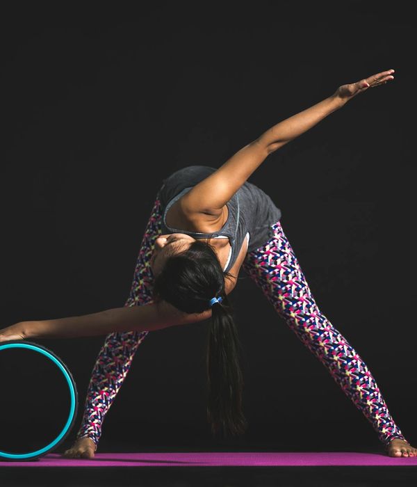 Woman in a calm yoga pose against a dark background with azure highlights.